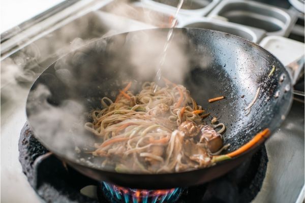Pad Thai haciéndose en el wok y echándose salsa por encima