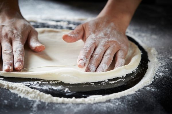 Manos estirando la masa de la pizza