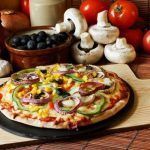 Pizza vegana en tabla de madera junto a varios ingredientes