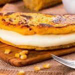 Cachapa venezolana rellena de queso sobre tabla de madera