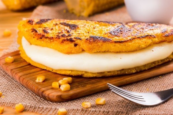 Cachapa venezolana rellena de queso sobre tabla de madera