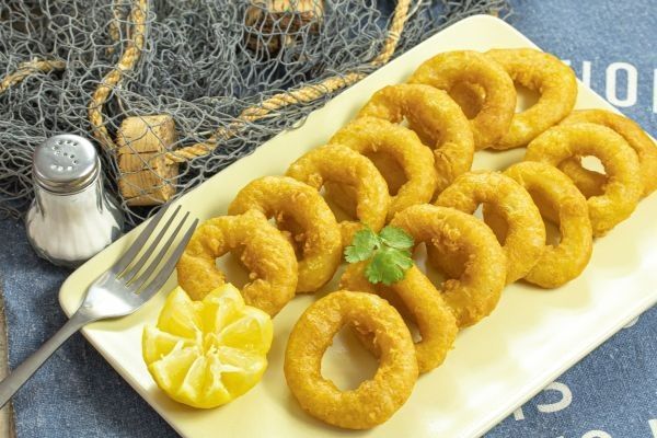 Calamares a la romana presentados en un plato con un limón y perejil