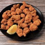 Cazón en adobo en plato negro sobre mesa de madera