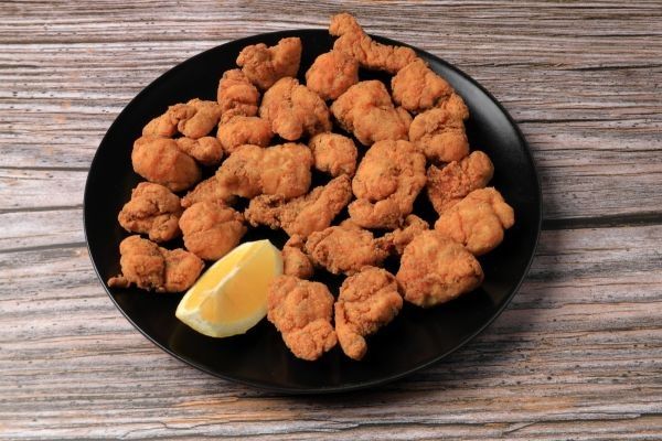 Cazón en adobo en plato negro sobre mesa de madera
