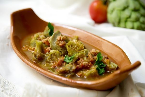 Alcachofas con jamón presentadas en plato de barro
