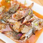 Cangrejo azul con verduras presentado en plato cuadrado blanco