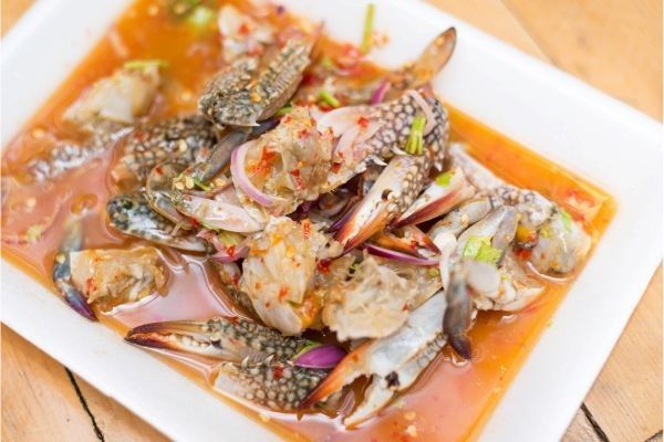 Cangrejo azul con verduras presentado en plato cuadrado blanco