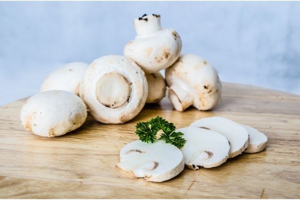 Champiñones cortados en laminas sobre tabla de madera