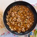 Gambas al pil pil presentadas en sartén junto a dos barras de pan