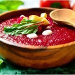 Gazpacho de remolacha presentado en cuenco de madera junto a cuchara