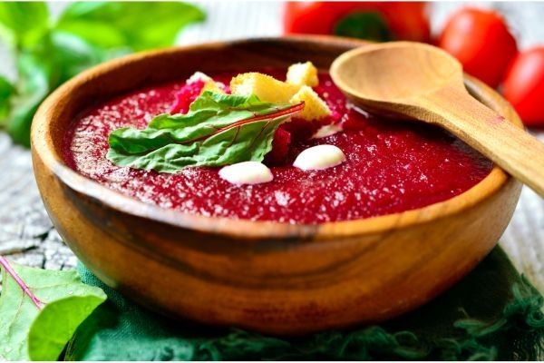 Gazpacho de remolacha presentado en cuenco de madera junto a cuchara