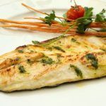 Lubina a la bilbaína presentada en plato blanco con verduras