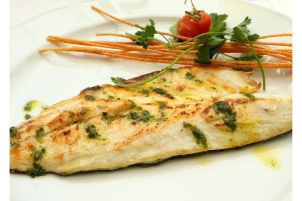Lubina a la bilbaína presentada en plato blanco con verduras