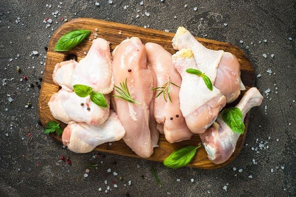 Pollo troceado crudo sobre tabla de madera