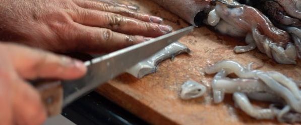 Chef cortando calamares en una tabla de madera