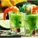Cóctel de gambas con aguacate y lima presentados en vasos individuales junto a rodajas de lima