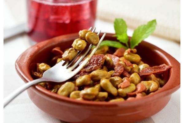 Habas con jamón en cazuela de barro con tenedor