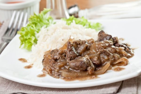 Hígado encebollado presentado en plato con arroz blanco