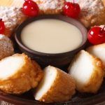 Leche frita casera presentada con leche condensada y cerezas de decoración