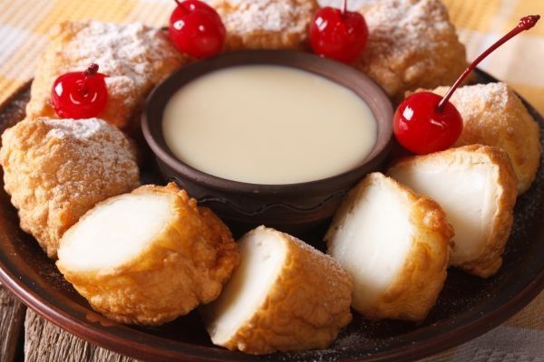 Leche frita casera presentada con leche condensada y cerezas de decoración