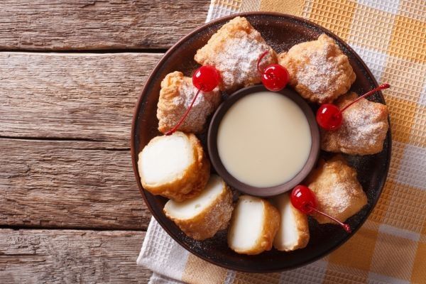 Leche frita casera presentada con leche condensada y cerezas de decoración vista desde arriba
