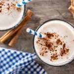 Vasos con leche merengada espolvoreados con canela y decorados alrededor con canela en rama