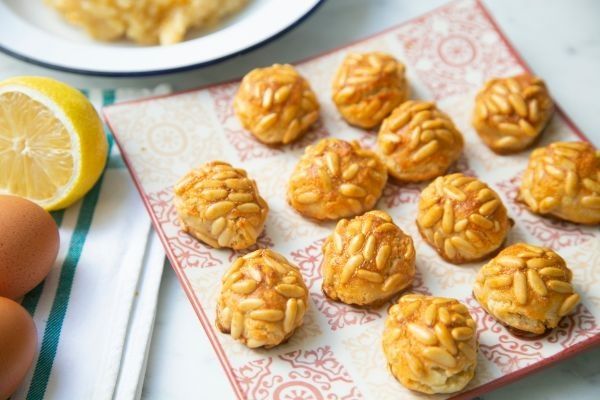 Panellets de piñones presentados en plato cuadrado junto sus ingredientes