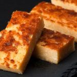 Quesada pasiega cortada en trozos y presentada sobre plato de pizarra negra