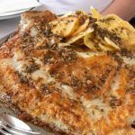 Rodaballo al horno servido con patatas en bandeja de metal