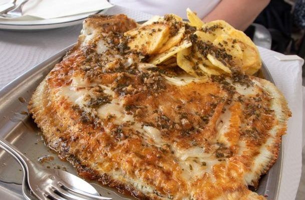 Rodaballo al horno servido con patatas en bandeja de metal