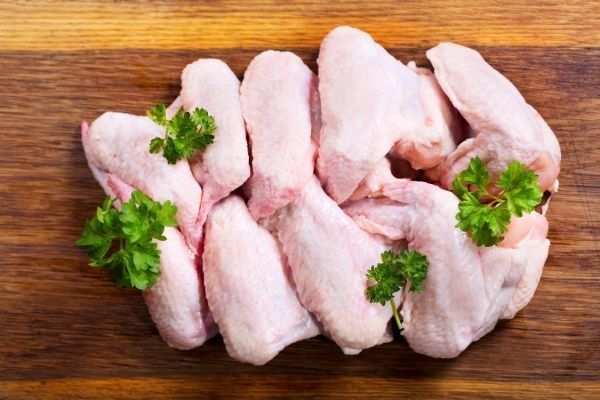 Alitas de pollo frescas sobre tabla de madera