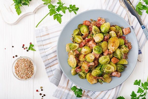 Coles de Bruselas con jamón y cebolla picada presentadas en plato blanco