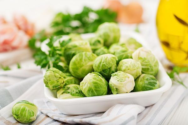 Coles de Bruselas limpias en un plato con ingredientes alrededor