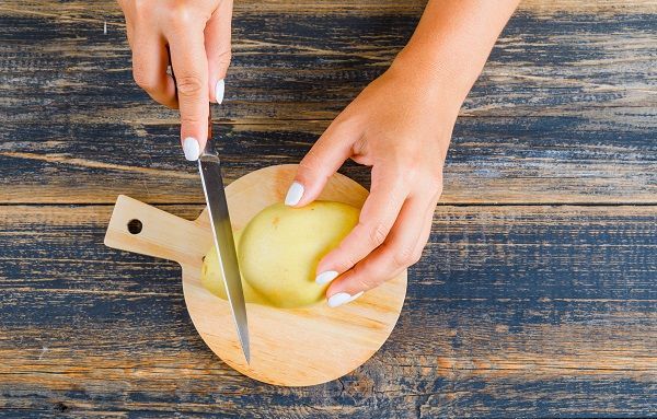 Manos de mujer cortando patatas