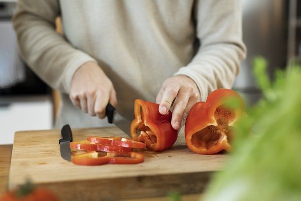Chef cortando pimiento rojo sobre una tabla de madera