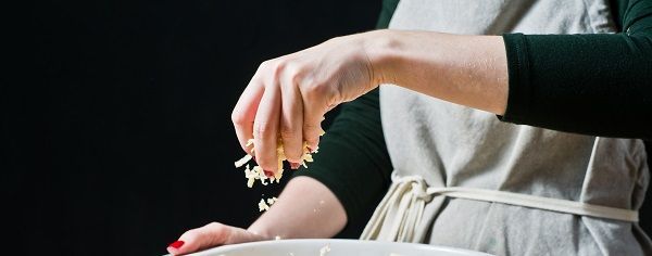 Chef espolvoreando parmesano en la fuente para horno