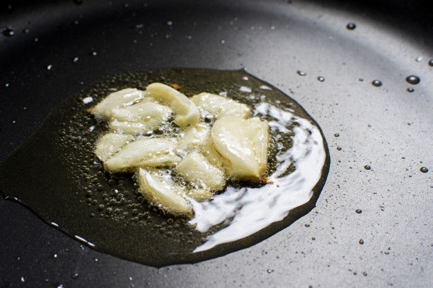 Garlic fry on a vegetable oil in a black hot pan.