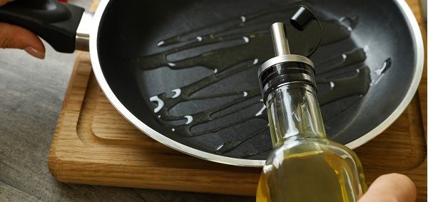 Chef echando aceite en una sartén