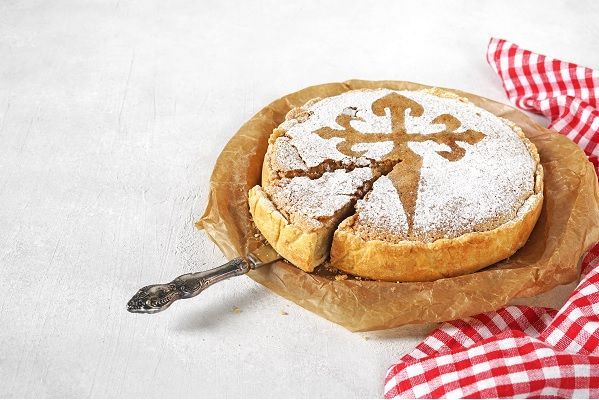 Tarta de Santiago presentada sobre plato con una cuchara sacando una porción