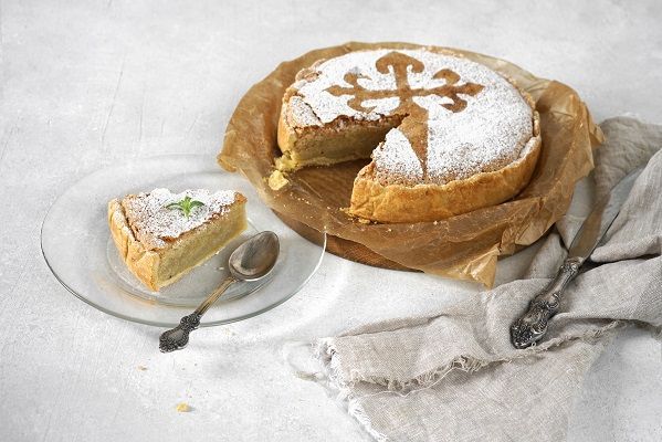 Tarta de Santiago con una porción cortada presentada en plato blanco y cuchara