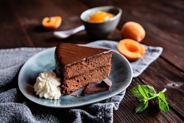 Tarta Sacher presentada en plato con un poco de nata y chocolate
