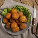 Arancini sicilianas presentadas en un plato decorado con lechuga