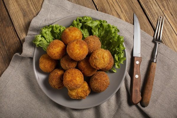 Arancini sicilianas presentadas en un plato decorado con lechuga