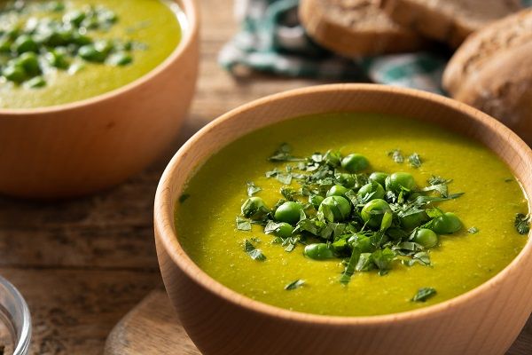 Crema de guisantes presentada en cuenco decorada con menta y guisantes
