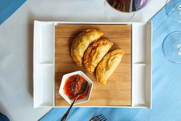 Empanadillas de atún al horno sobre tabla de madera junto a deliciosa salsa