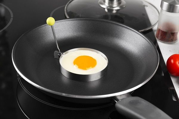 Huevo frito friéndose en la sartén en un molde circular para que no pierda la forma