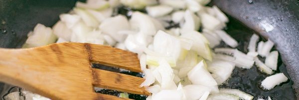 Cebolla haciéndose en la sartén con cuchara de madera