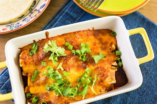 Enchilada de pollo recién hecha presentada en fuente blanca para horno