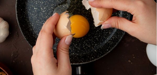 Chef rompiendo un huevo para freírlo