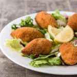 Mejillones tigre rellenos presentados en plato blanco con limón en el centro